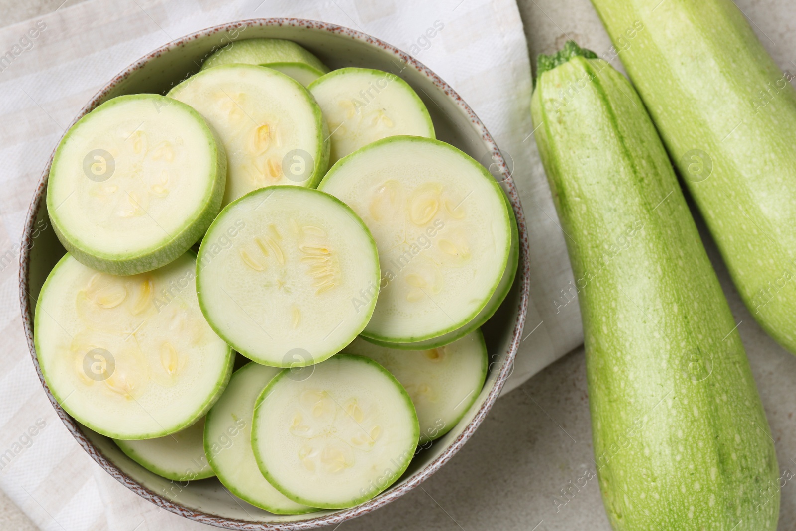 Photo of Fresh cut and whole zucchinis on grey textured table, flat lay