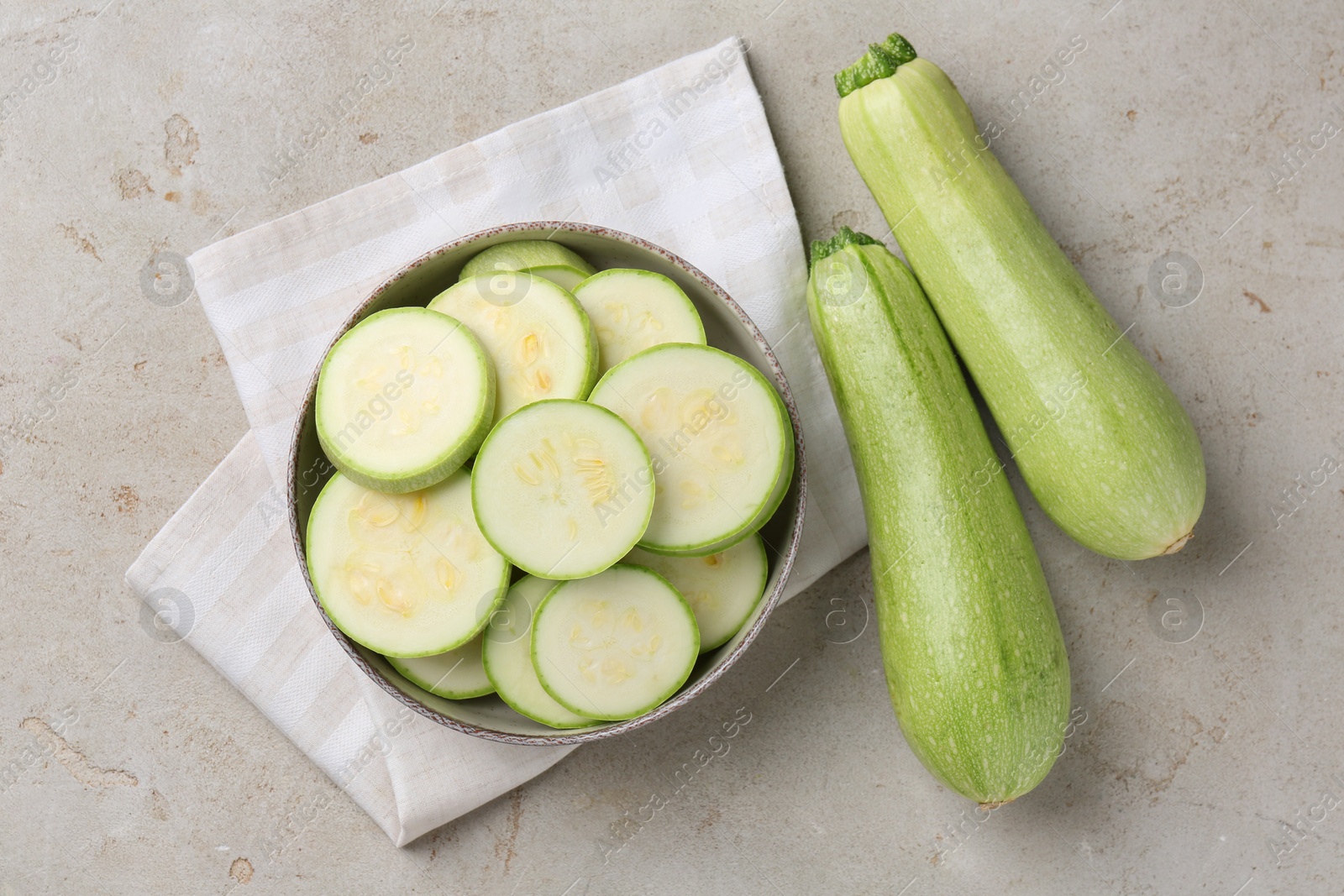 Photo of Fresh cut and whole zucchinis on grey textured table, flat lay