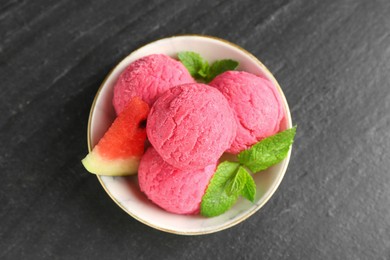 Photo of Scoops of tasty watermelon sorbet with mint and fresh fruit in bowl on grey textured table, top view