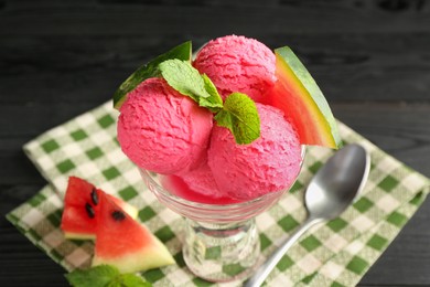 Photo of Scoops of tasty watermelon sorbet in glass dessert bowl with fresh fruit and spoon on black table, closeup