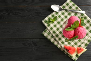 Photo of Scoops of tasty watermelon sorbet in glass dessert bowl with fresh fruit and spoon on black wooden table, flat lay. Space for text