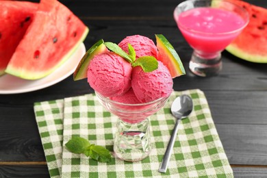 Photo of Scoops of tasty watermelon sorbet with mint, fresh fruit in glass dessert bowl and spoon on wooden table