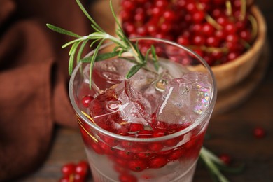 Photo of Refreshing water with red currants and rosemary in glass on table, closeup