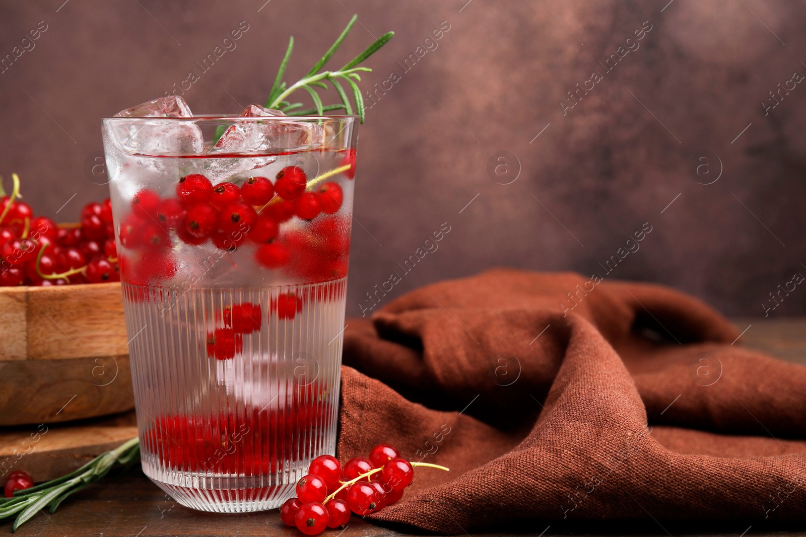 Photo of Refreshing water with red currants and rosemary in glass on table, space for text