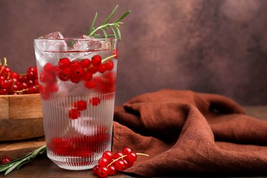 Photo of Refreshing water with red currants and rosemary in glass on table, space for text