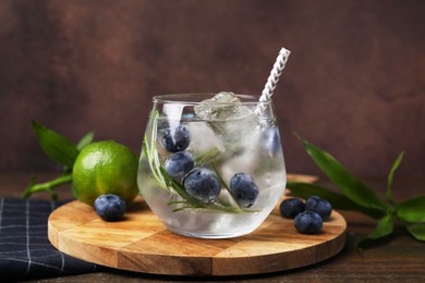 Photo of Refreshing water with blueberries and rosemary in glass on wooden table