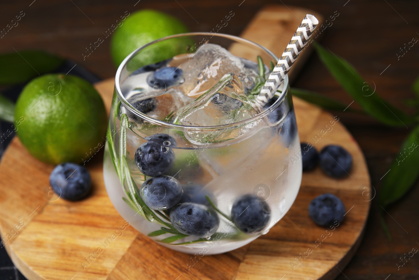 Photo of Refreshing water with blueberries and rosemary in glass on table, closeup