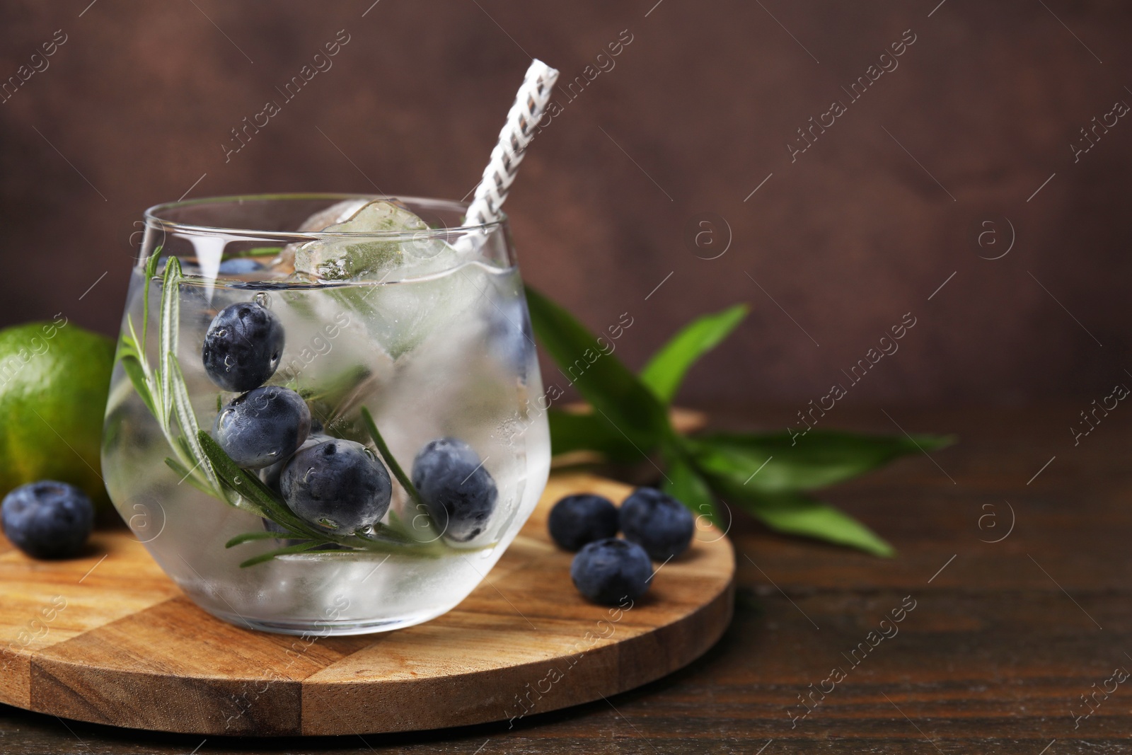 Photo of Refreshing water with blueberries and rosemary in glass on wooden table, space for text