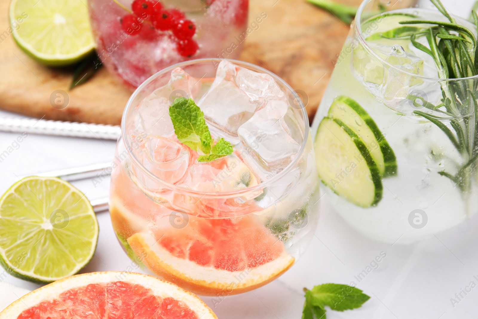 Photo of Different refreshing drinks in glasses on white tiled table, closeup