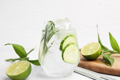 Photo of Refreshing water with cucumber and rosemary in glass on white table