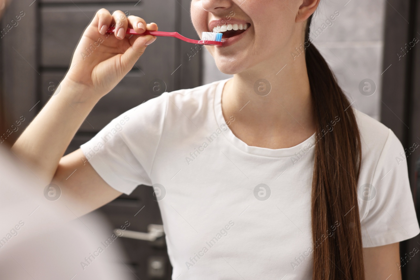 Photo of Woman brushing her teeth in bathroom, closeup