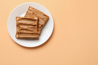 Photo of Delicious sandwiches with peanut butter on pale orange table, top view. Space for text