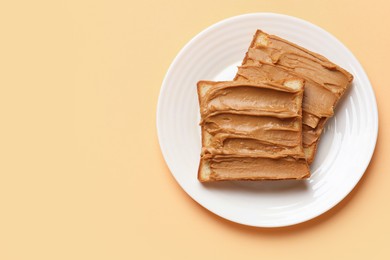 Photo of Delicious sandwiches with peanut butter on pale orange table, top view. Space for text