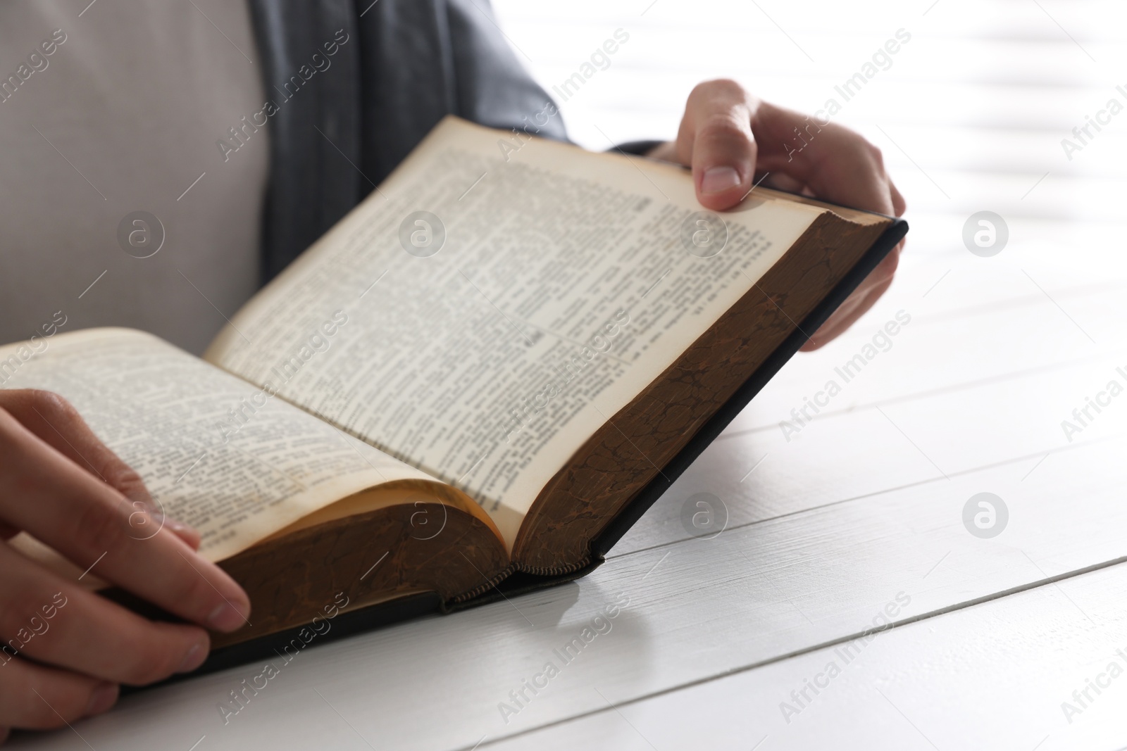 Photo of Man with Bible at white wooden table, closeup