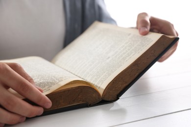 Photo of Man with Bible at white wooden table, closeup