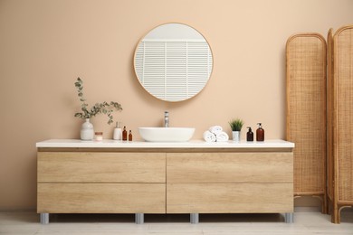 Photo of Folding screen, vanity, sink, mirror and floral decor in bathroom. Interior design