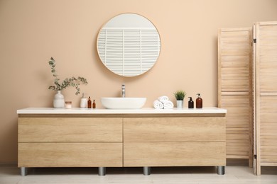 Photo of Folding screen, vanity, sink, mirror and floral decor in bathroom. Interior design