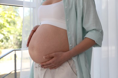 Photo of Young pregnant woman at home, closeup view