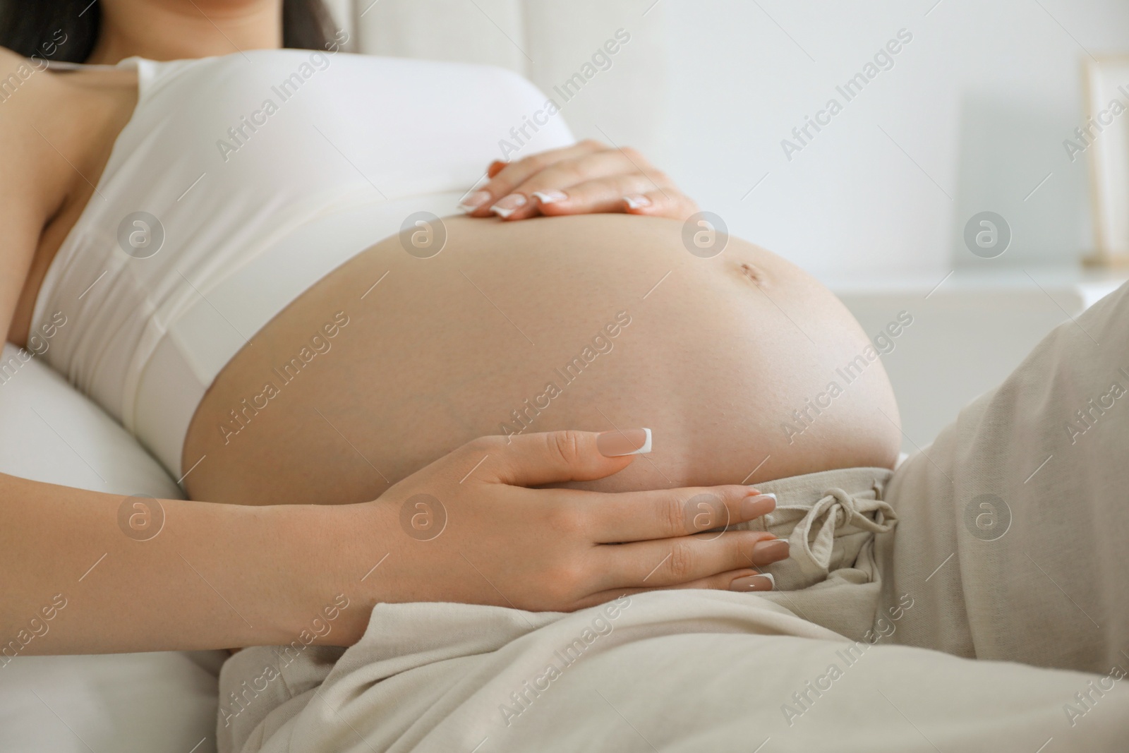 Photo of Young pregnant woman lying on bed at home, closeup