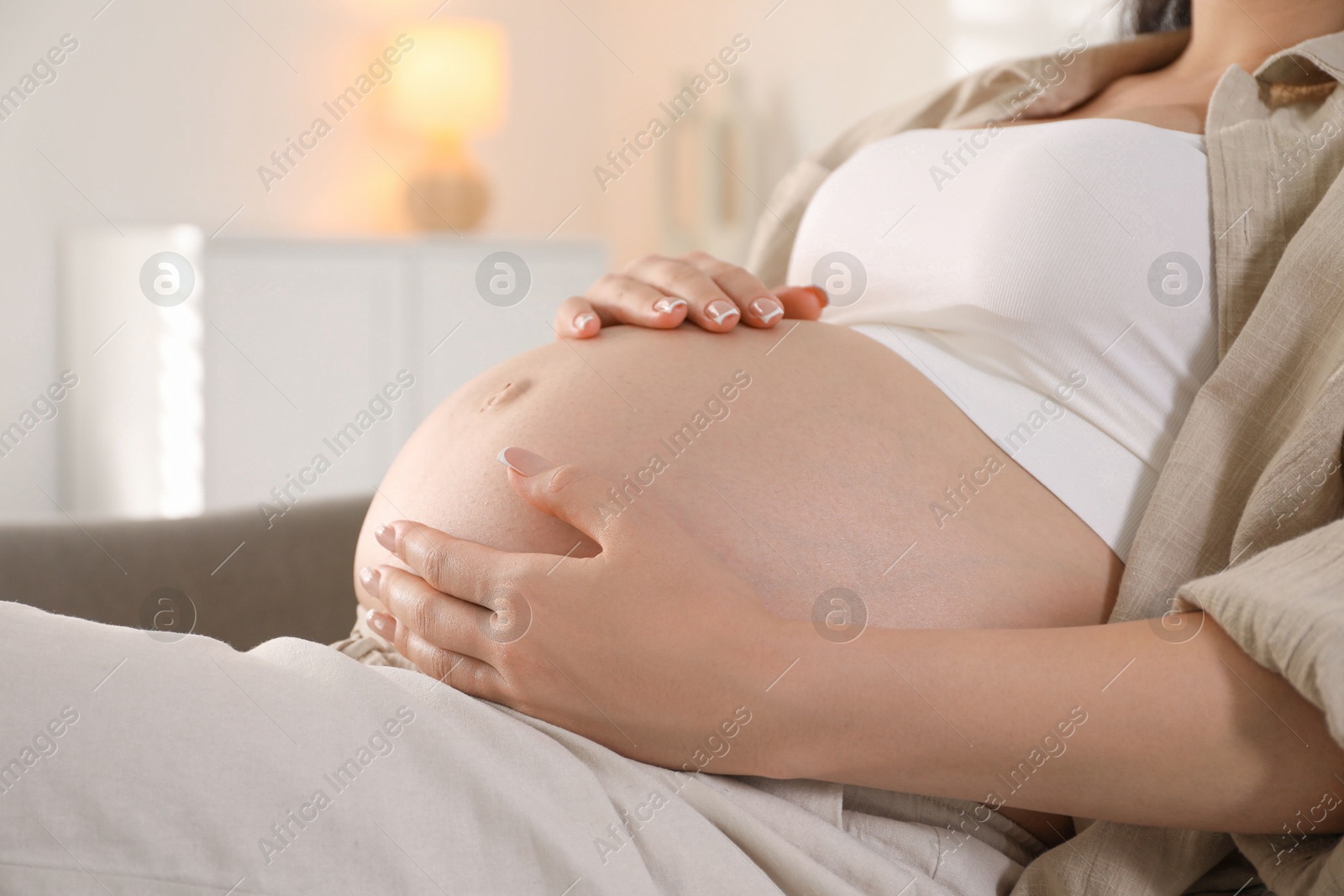 Photo of Young pregnant woman lying on bed at home, closeup