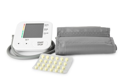 Photo of Blood pressure monitor and pills in blister isolated on white