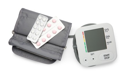 Photo of Blood pressure monitor and pills in blisters isolated on white, top view