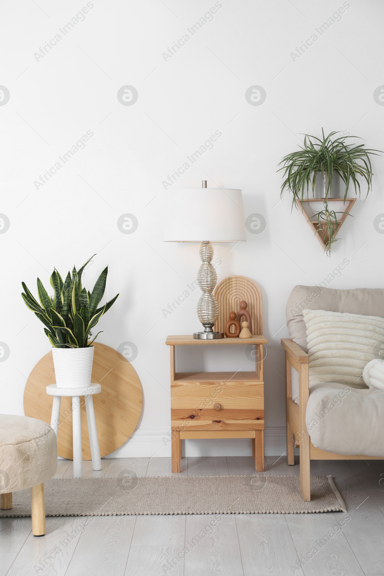 Photo of Stool, sofa, lamp and houseplants in room. Interior design