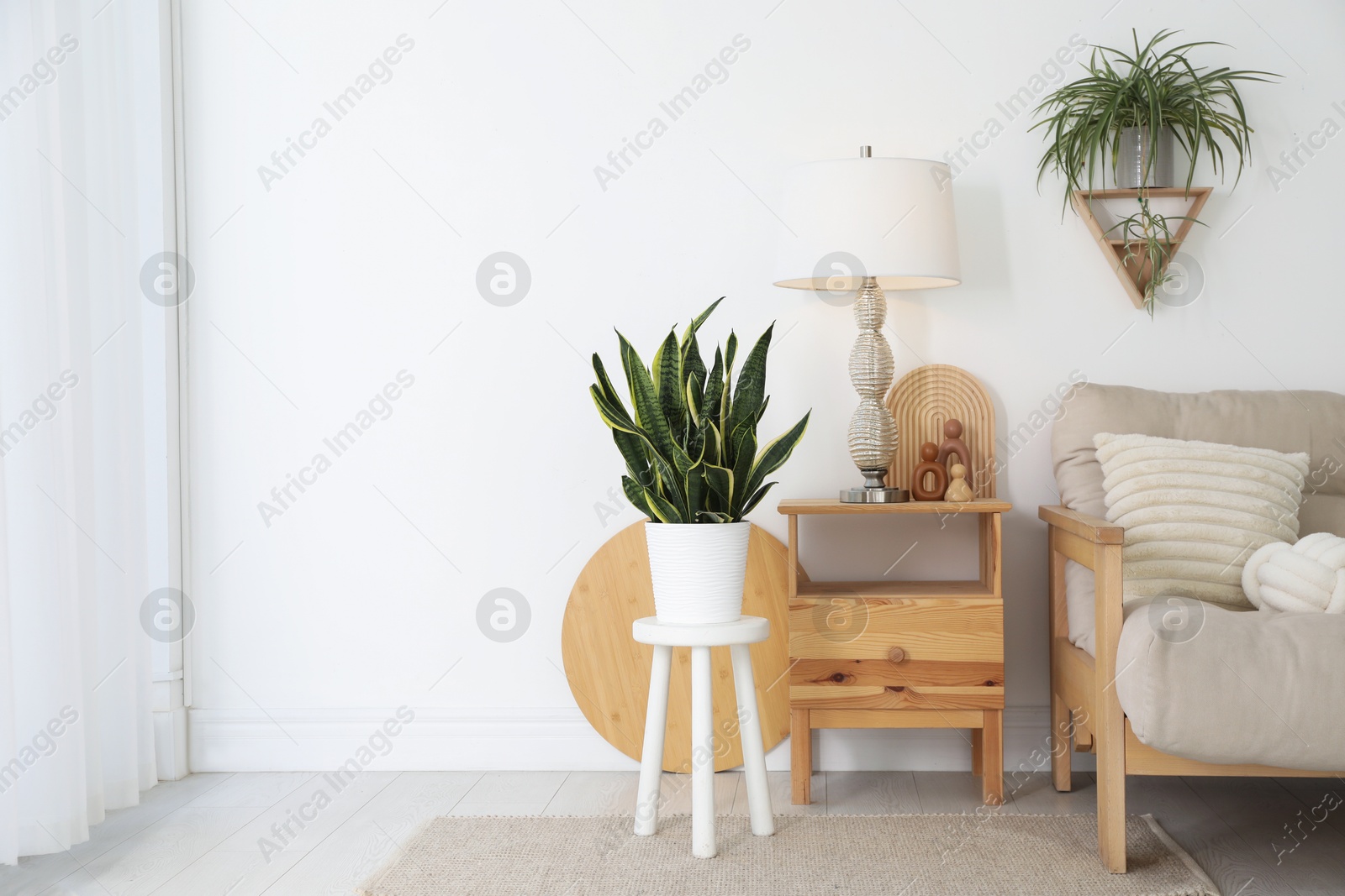 Photo of Stool, sofa, lamp and houseplants in room. Interior design