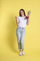 Happy winner with gold trophy cup on yellow background