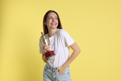 Happy winner with gold trophy cup on yellow background