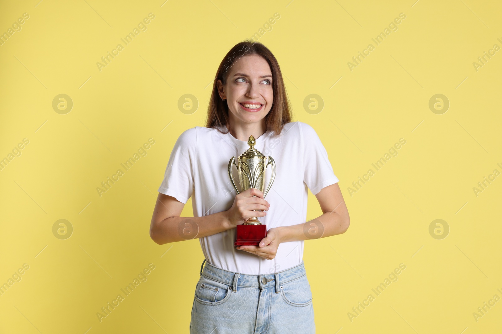 Photo of Happy winner with gold trophy cup on yellow background