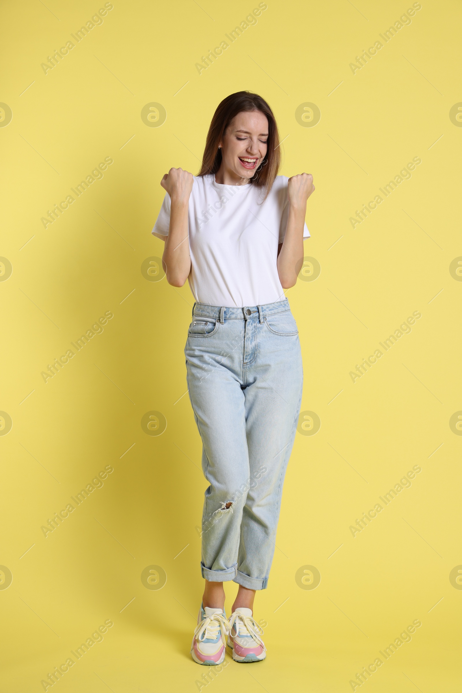 Photo of Portrait of happy winner on yellow background