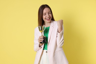 Happy winner with gold trophy cup on yellow background