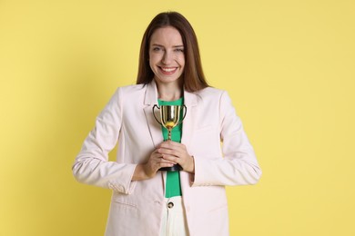 Happy winner with gold trophy cup on yellow background