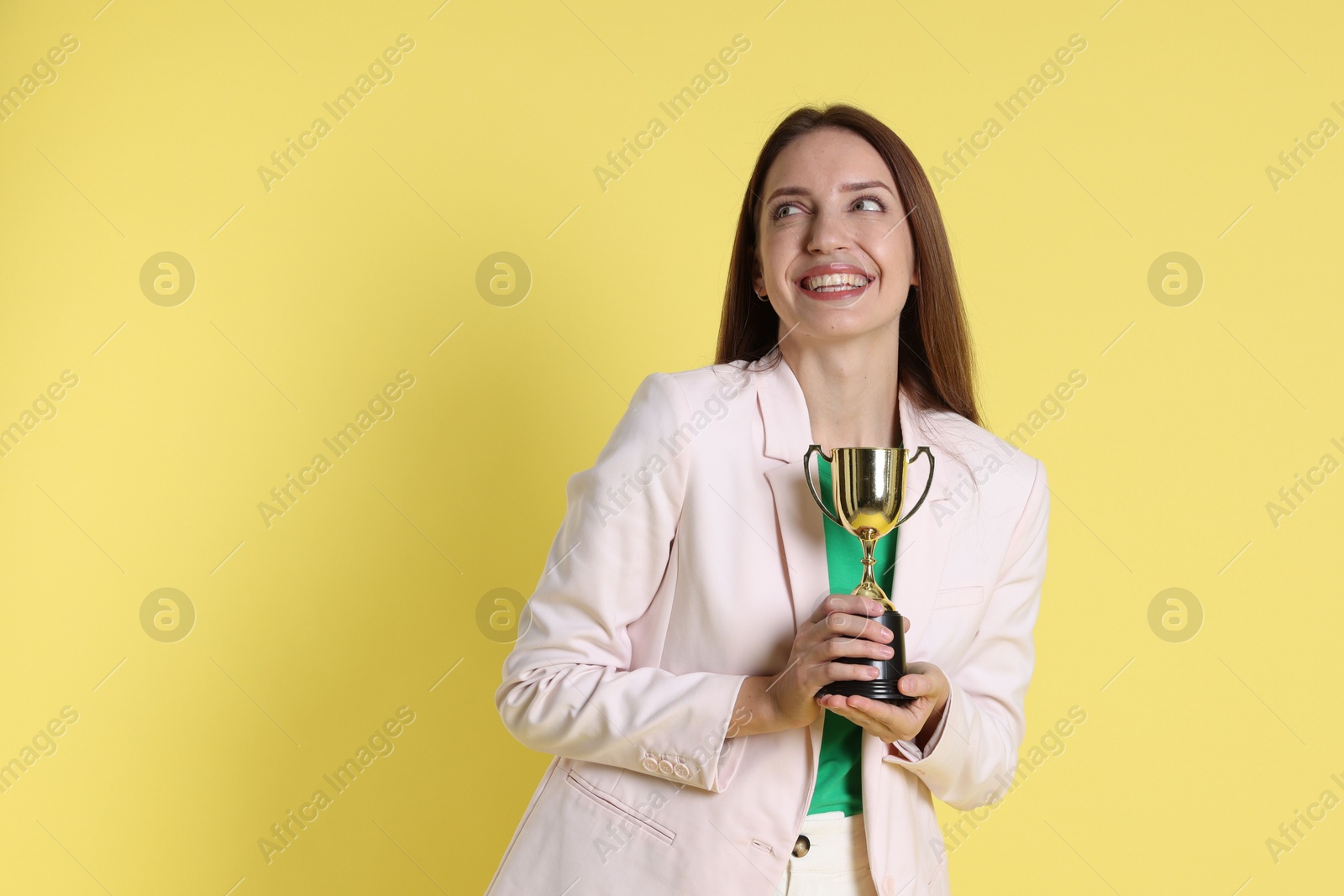 Photo of Happy winner with gold trophy cup on yellow background