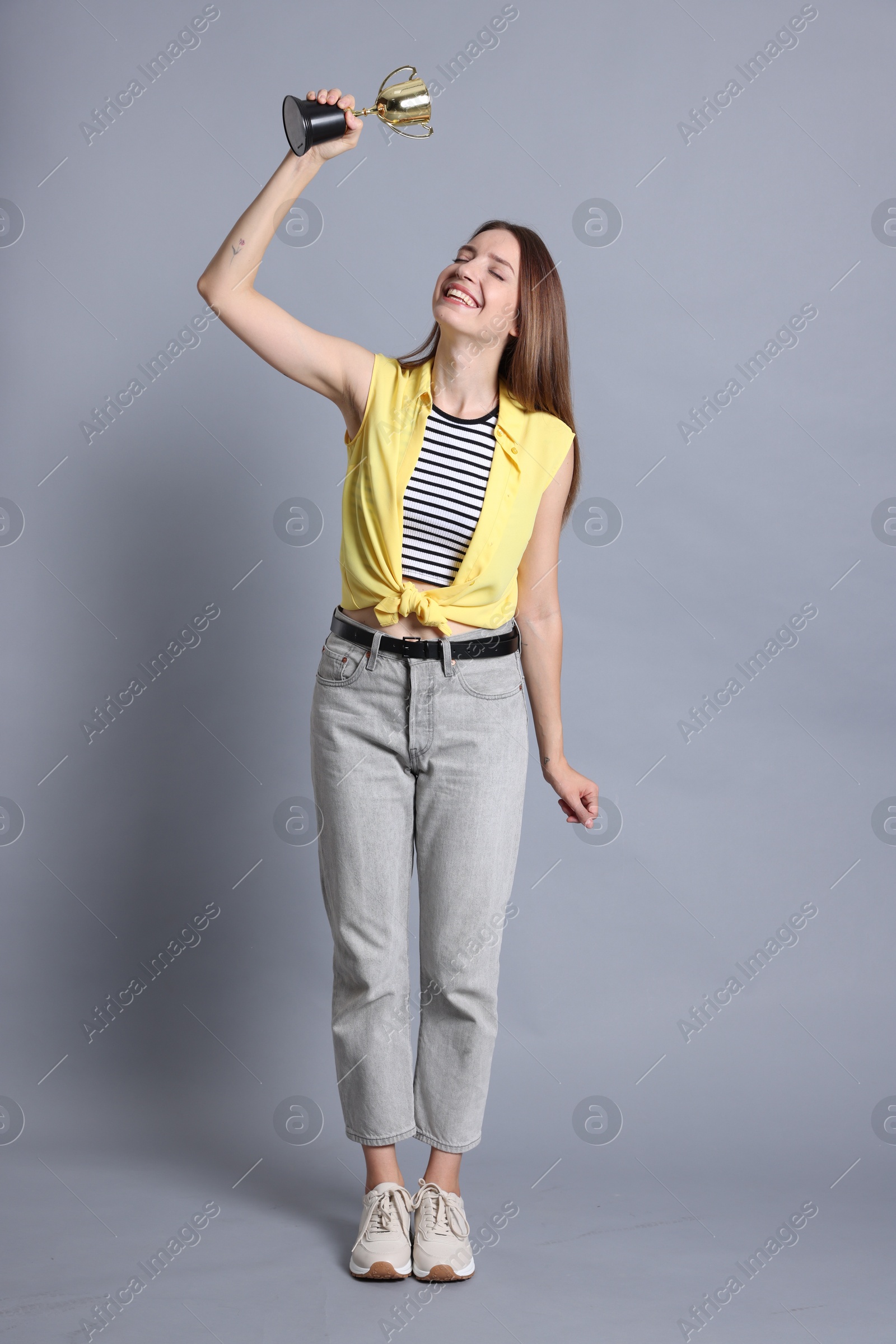 Photo of Happy winner with gold trophy cup on gray background