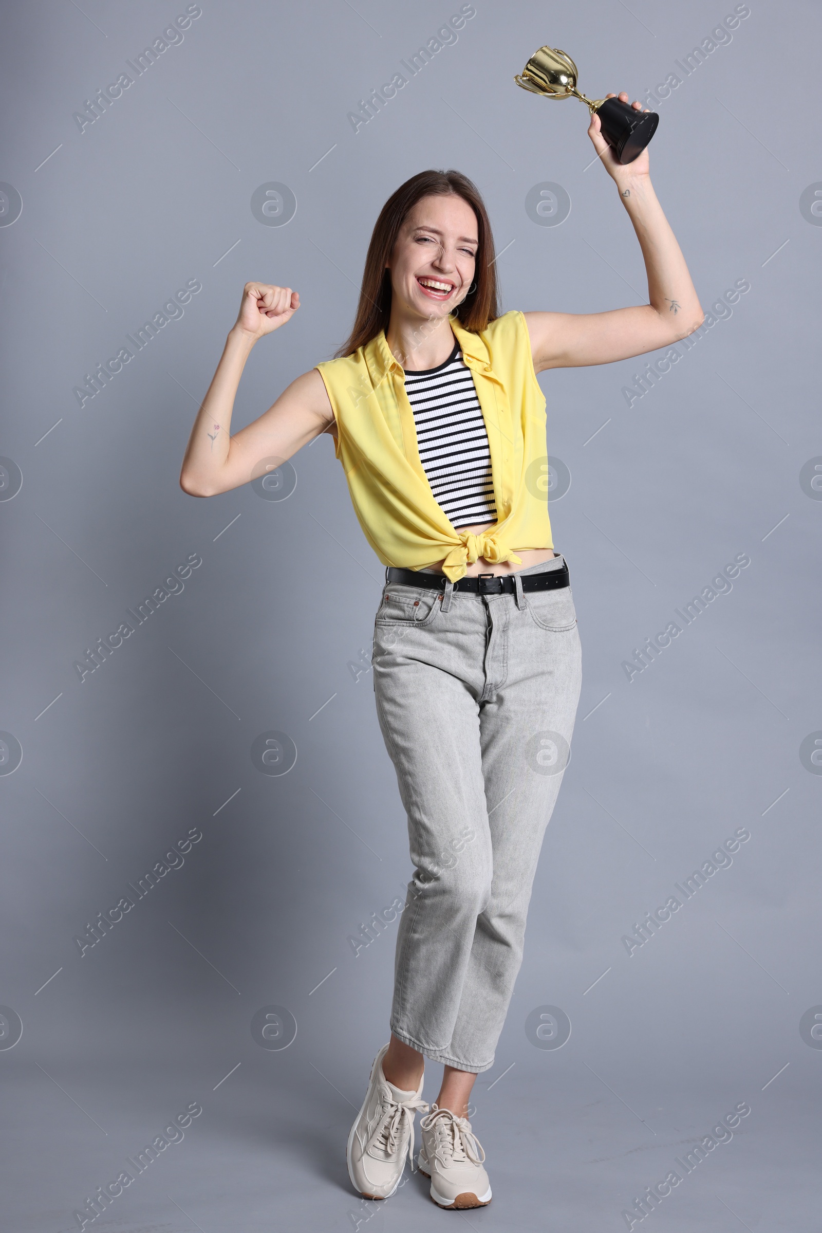 Photo of Happy winner with gold trophy cup on gray background