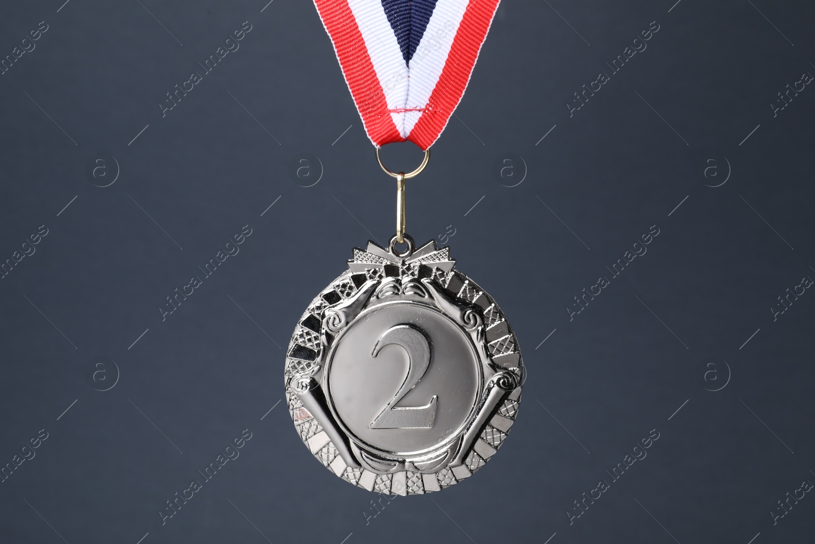 Photo of Silver medal with striped ribbon on grey background