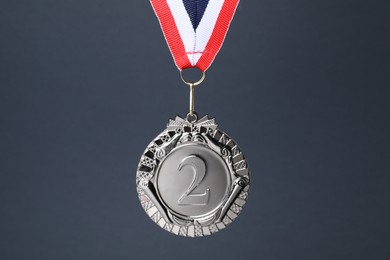 Photo of Silver medal with striped ribbon on grey background