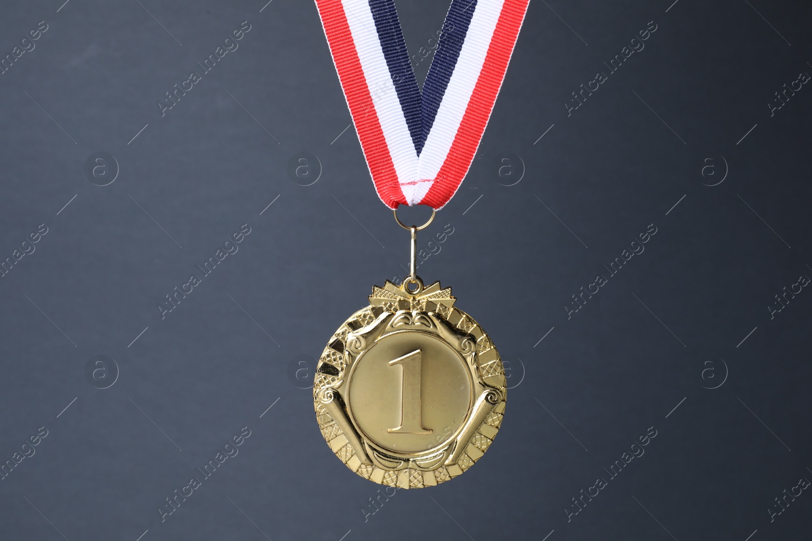 Photo of Golden medal with striped ribbon on grey background