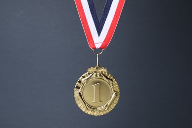 Photo of Golden medal with striped ribbon on grey background