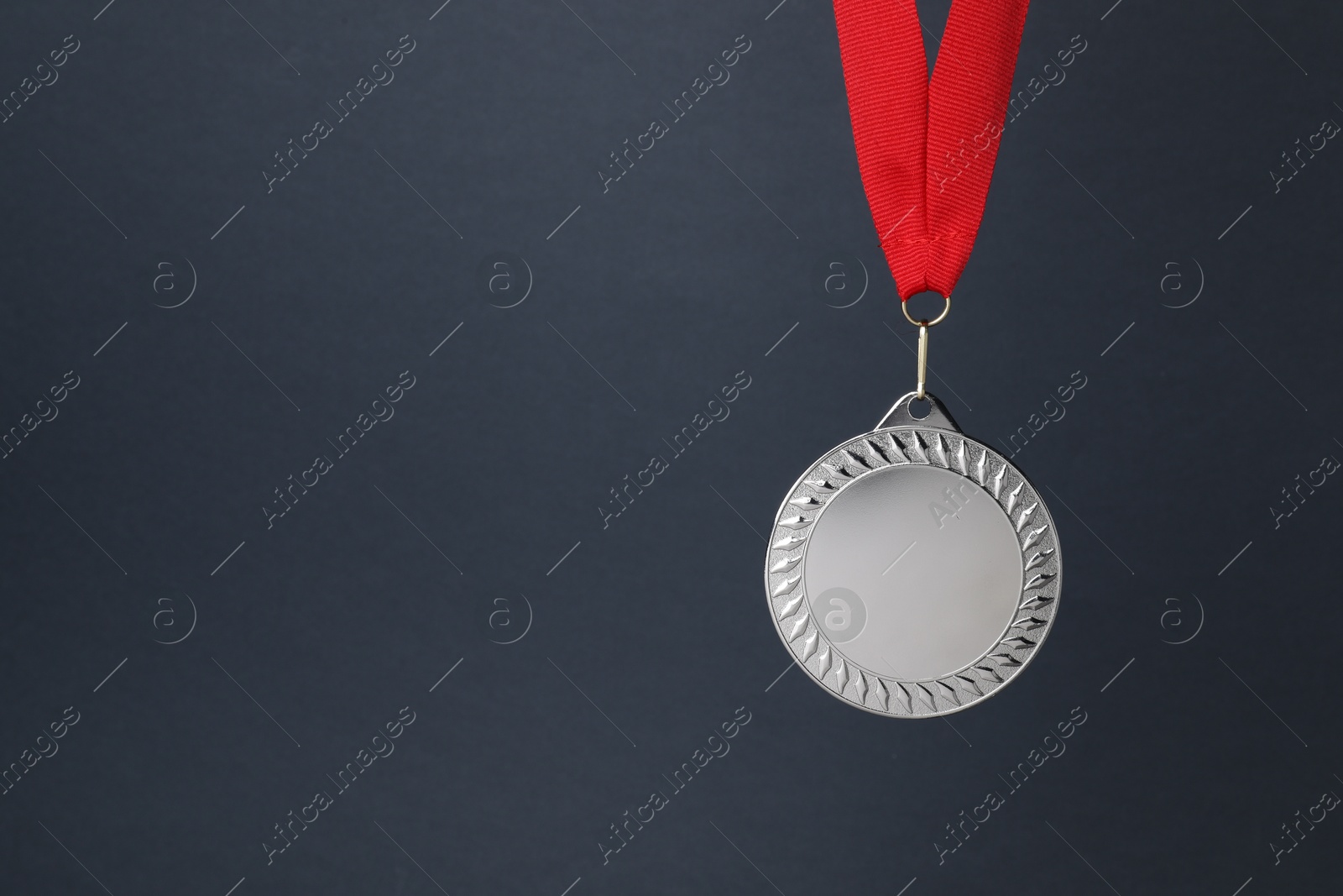 Photo of Silver medal with red ribbon on dark grey background, space for text