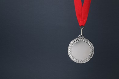 Photo of Silver medal with red ribbon on dark grey background, space for text