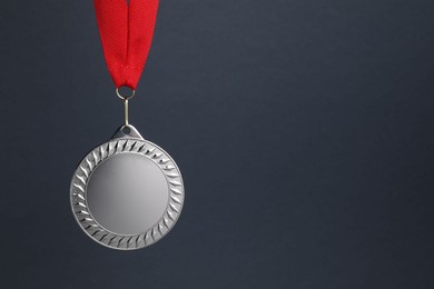 Photo of Silver medal with red ribbon on dark grey background, space for text