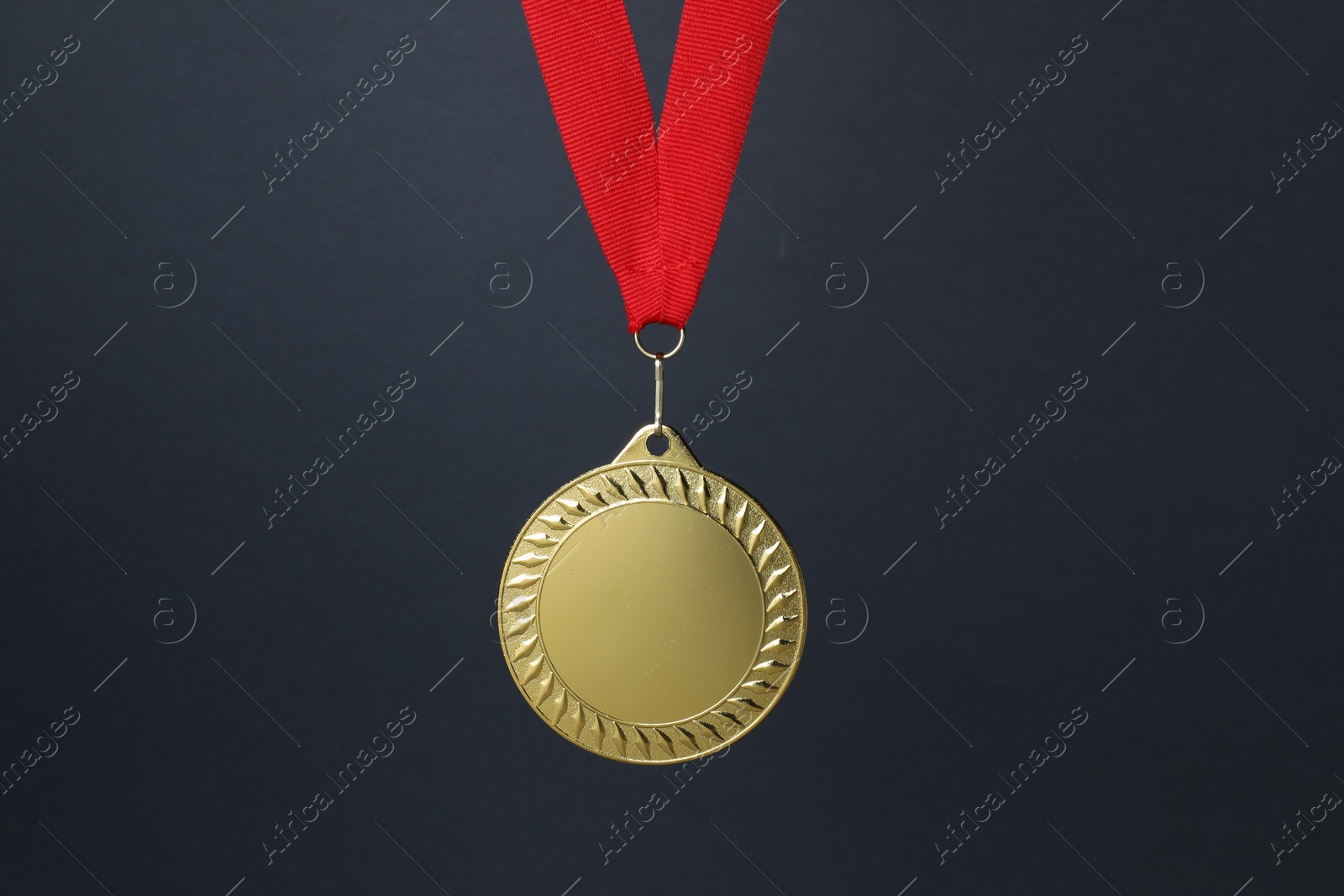 Photo of Golden medal with red ribbon on dark grey background