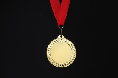 Photo of Golden medal with red ribbon on black background