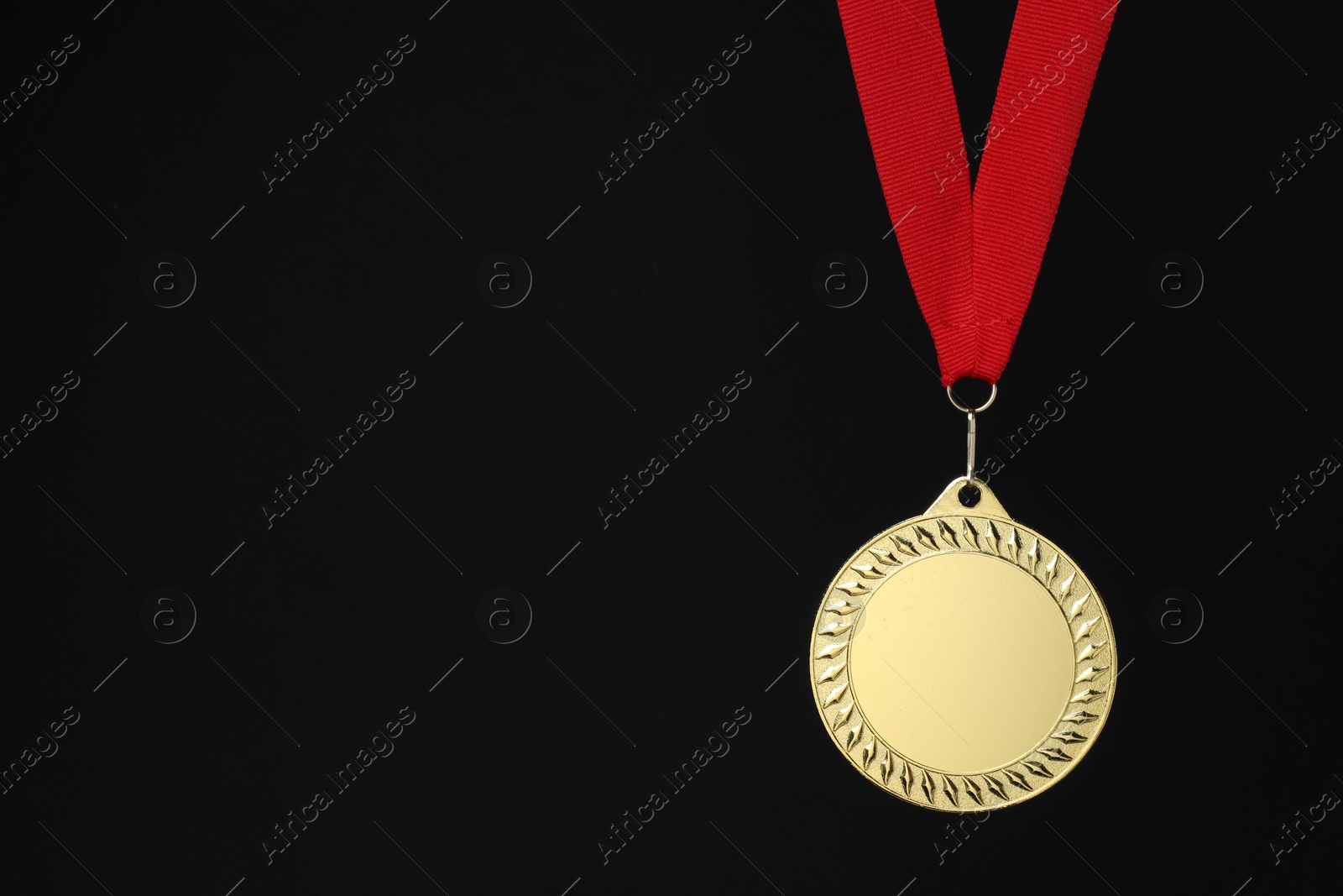 Photo of Golden medal with red ribbon on black background, space for text