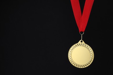 Photo of Golden medal with red ribbon on black background, space for text