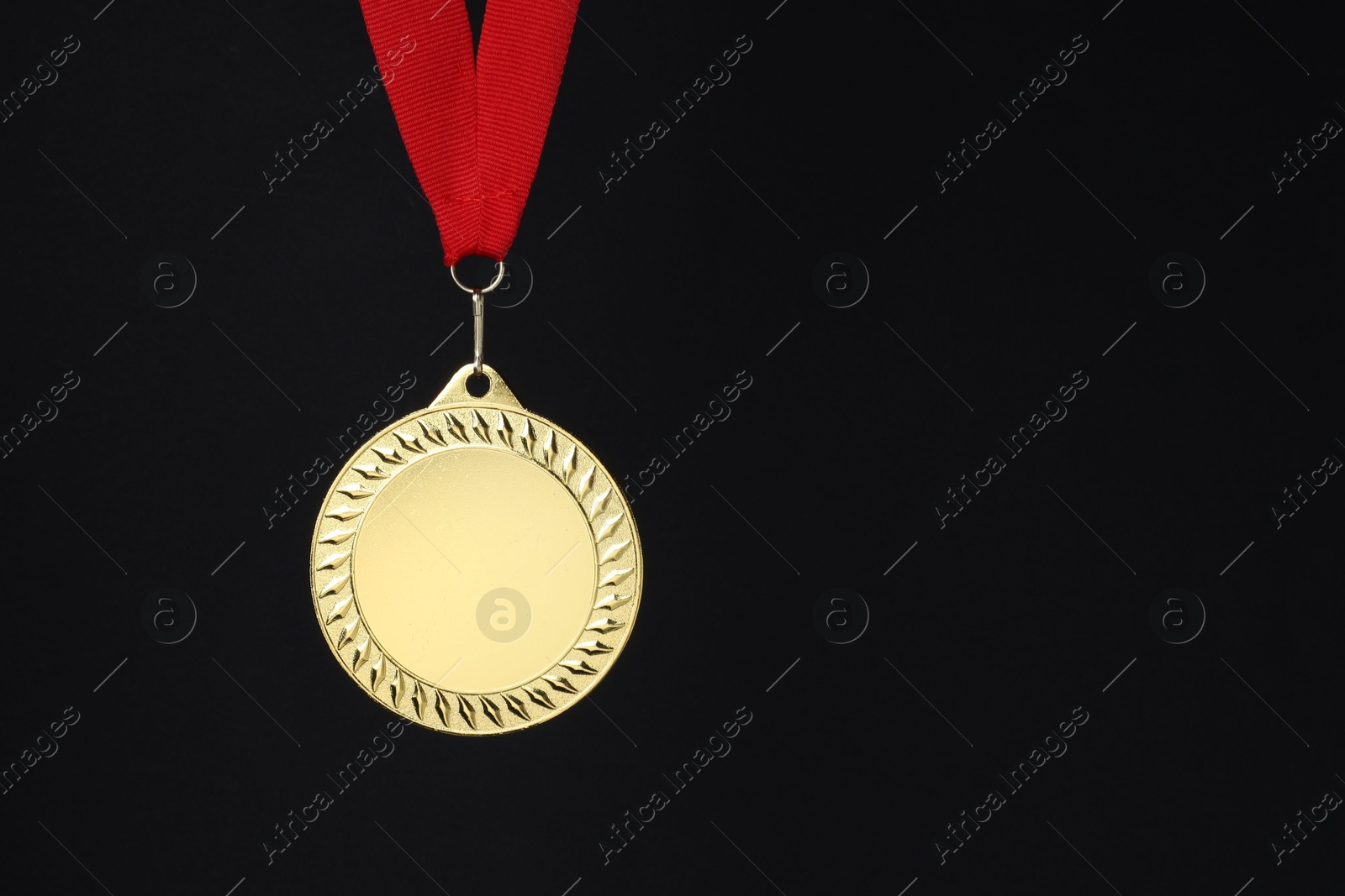 Photo of Golden medal with red ribbon on black background, space for text