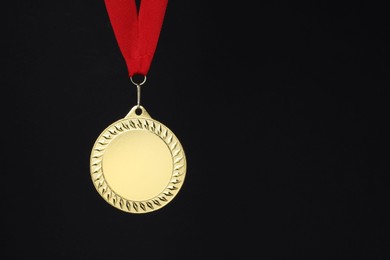 Photo of Golden medal with red ribbon on black background, space for text